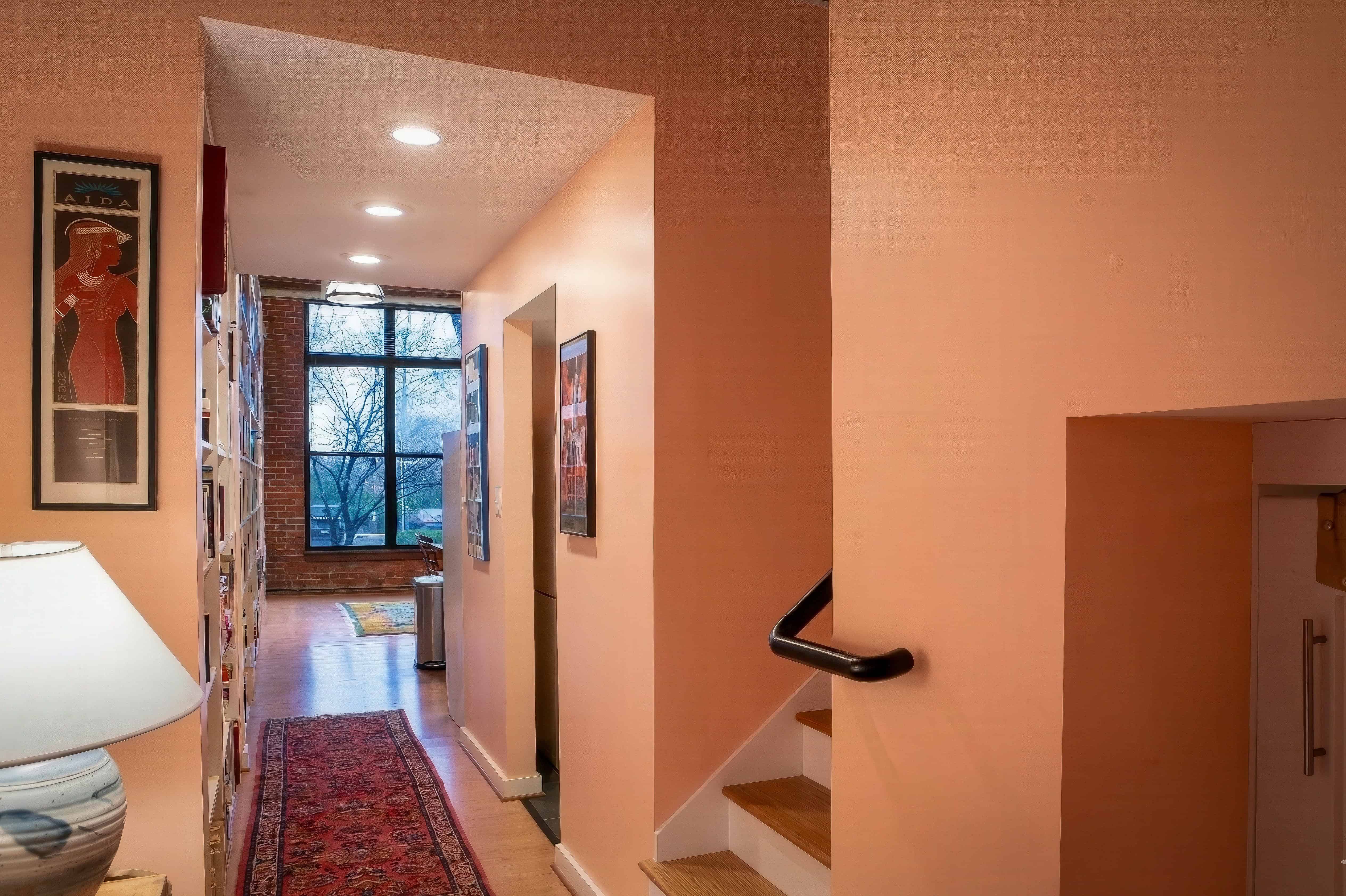Bright hallway with artwork and a view of the outdoors through large windows.