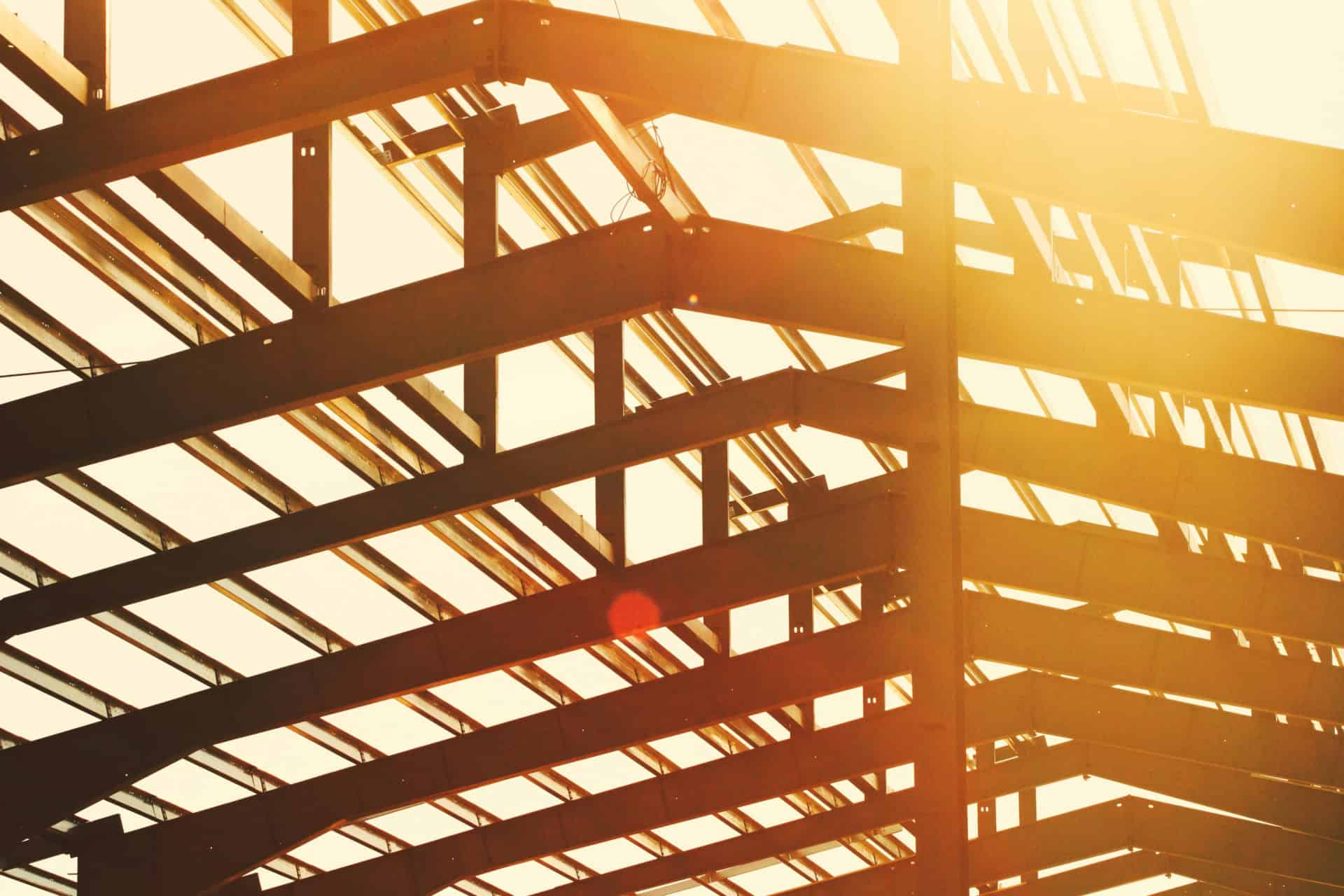 Steel building framework under construction with sunlight shining through.