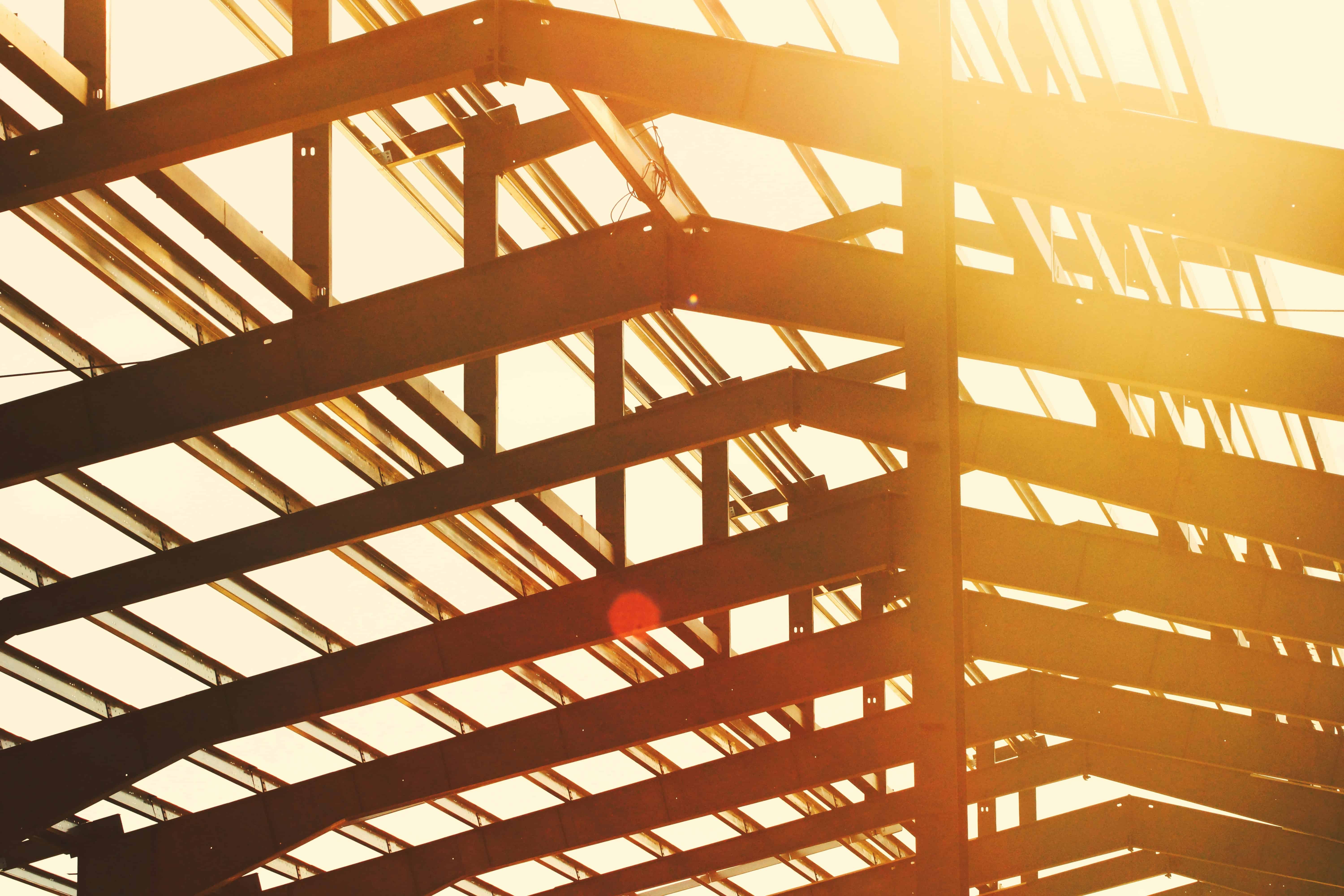 Steel building framework under construction with sunlight shining through.