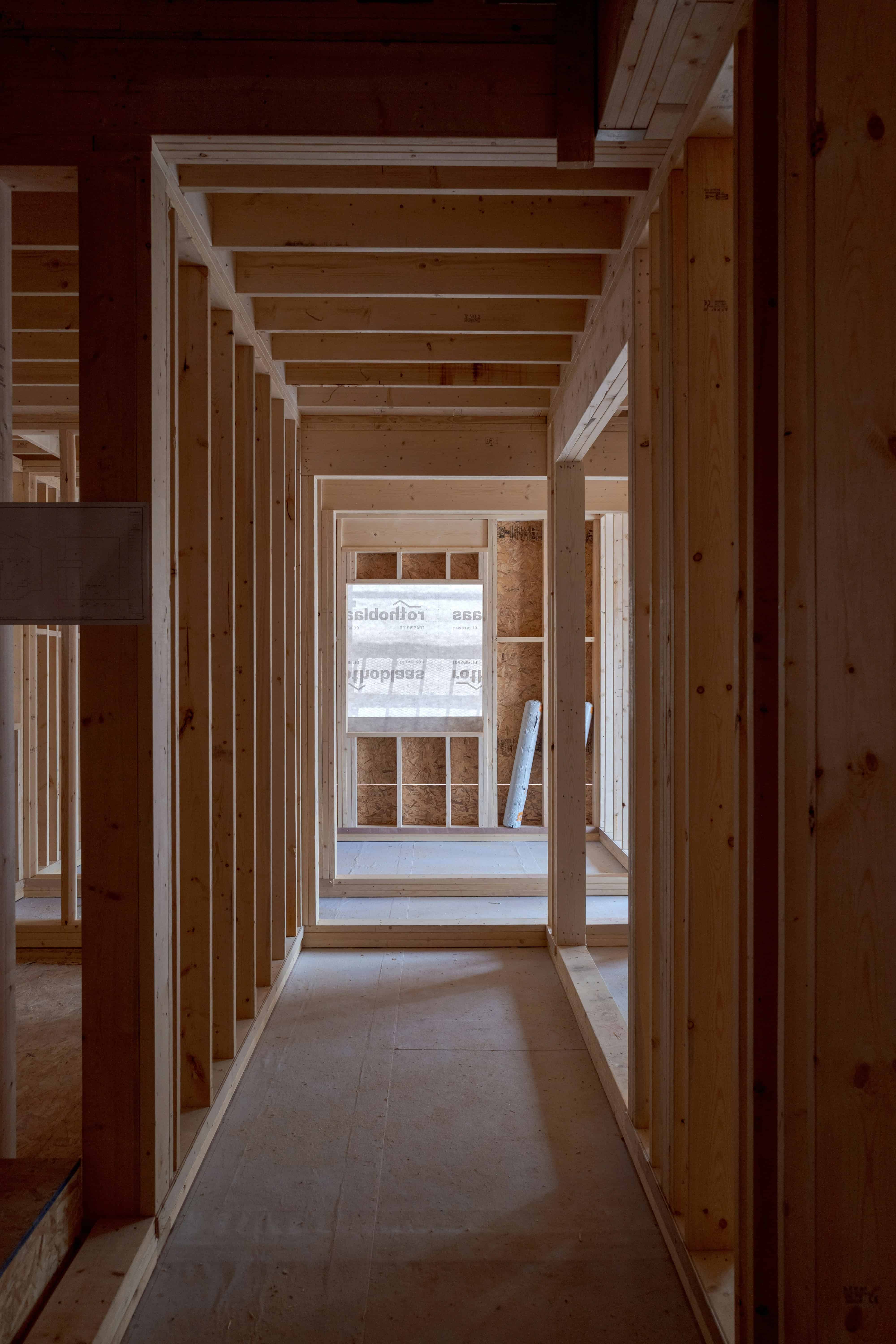 Wooden interior framing of a house under construction with visible studs and beams.