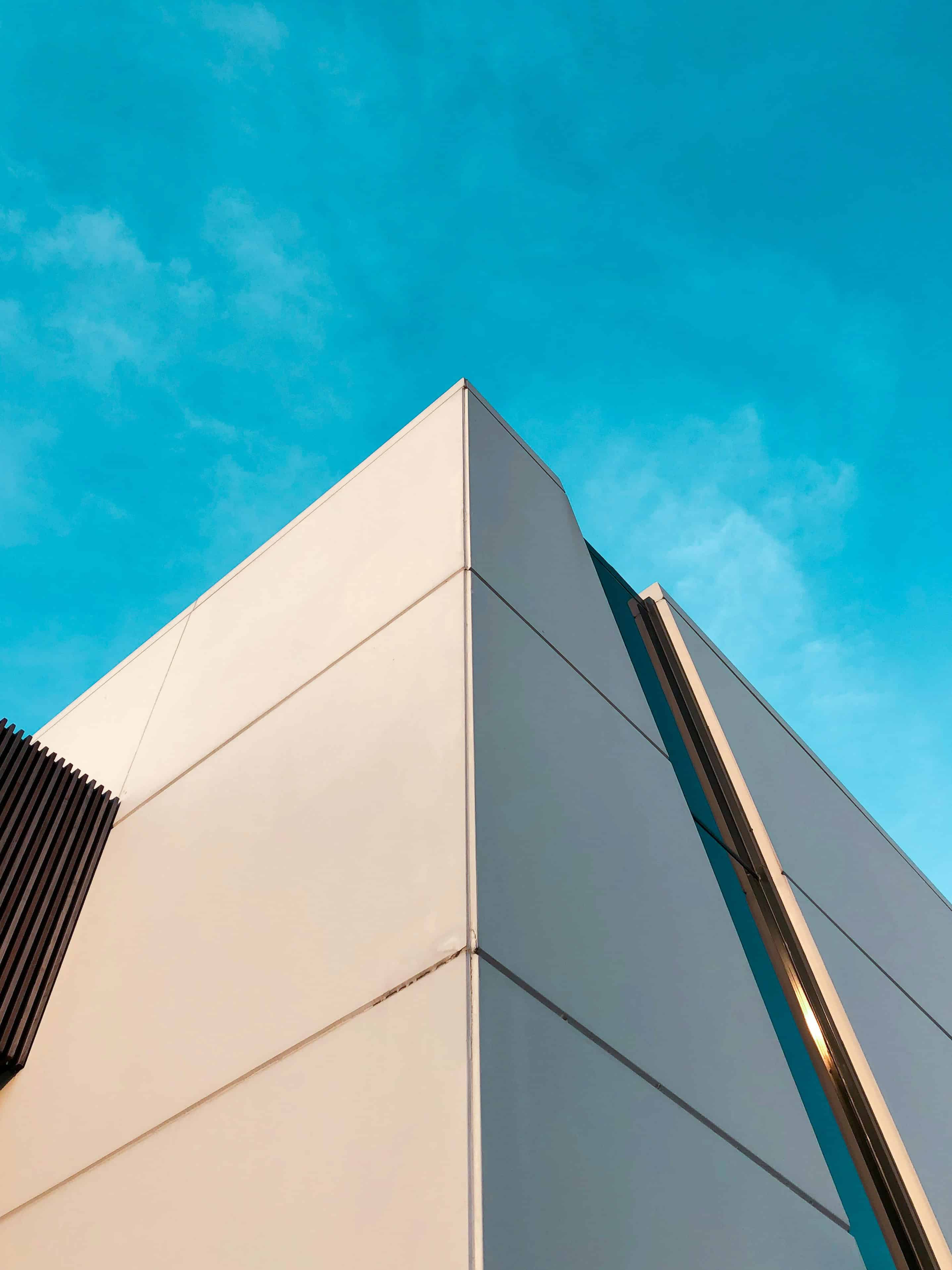 Contemporary building with sleek white panels and blue sky background.