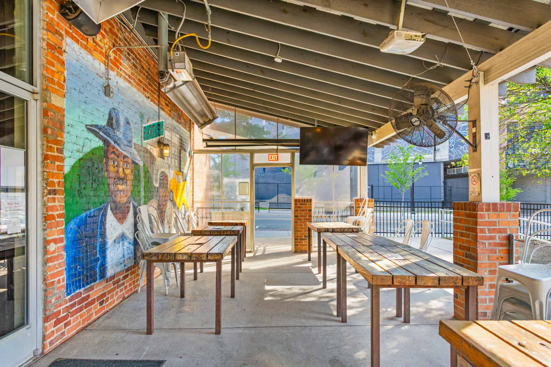 Outdoor patio with brick walls, wooden tables, and mural at Incline Construction Inc.
