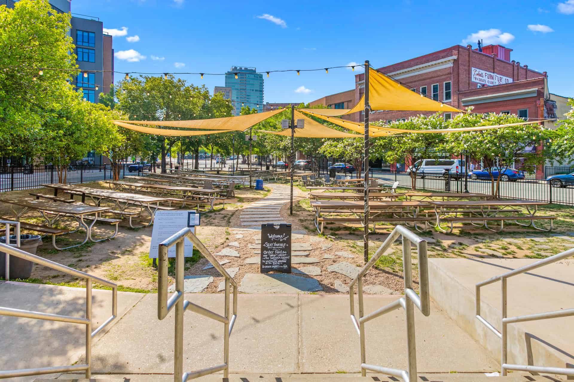 Outdoor seating with yellow shade sails in downtown area.